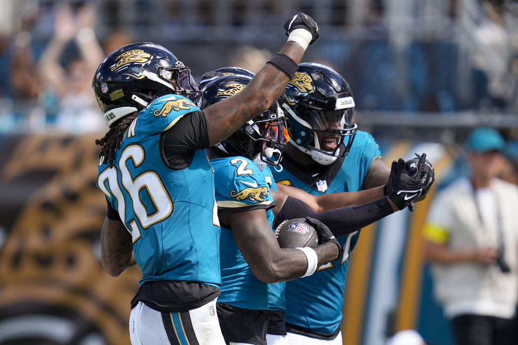 Jacksonville Jaguars cornerback Jourdan Lewis, center, celebrates an interception with teammates safety Antonio Johnson (26) and defensive end Josh Hines-Allen during the second half of an NFL football game against the Houston Texans Sunday, Sept. 21, 2025, in Jacksonville, Fla. (AP Photo/John Raoux)