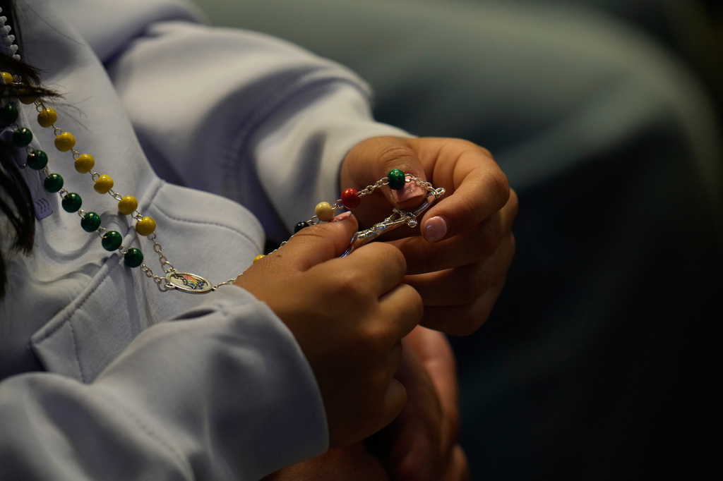 A woman holds a rosary as she attends a vigil for peace lead by Pope Leo XIV inside St. Peter's Basilica at the Vatican, Saturday, April 11, 2026. (AP Photo/Gregorio Borgia)