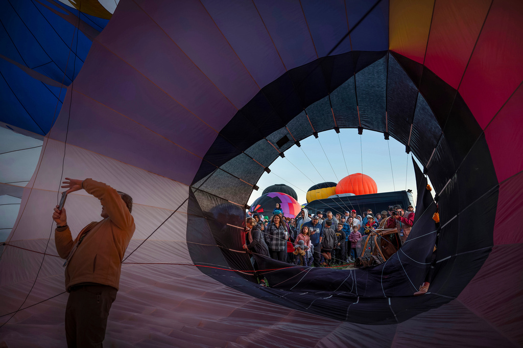 FILE - Pilot Mark Meyer, of North Carolina, takes a photo inside the Carnival special shape balloon as a crowd gathers around during the Albuquerque International Balloon Fiesta's Special Shape Rodeo and balloon launch at Balloon Fiesta Park in Albuquerque, N.M., Oct. 10, 2024. (Chancey Bush/The Albuquerque Journal via AP, File)