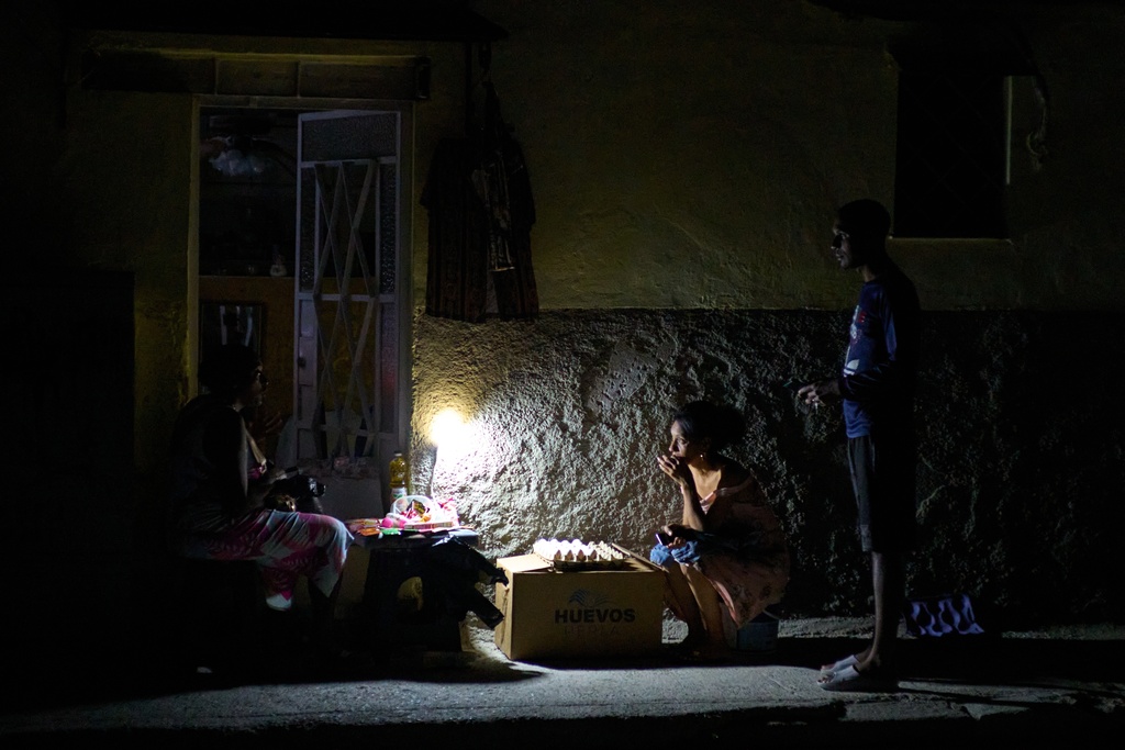 Street vendors chat during a blackout in Havana, Monday, March 16, 2026. (AP Photo/Ramon Espinosa)