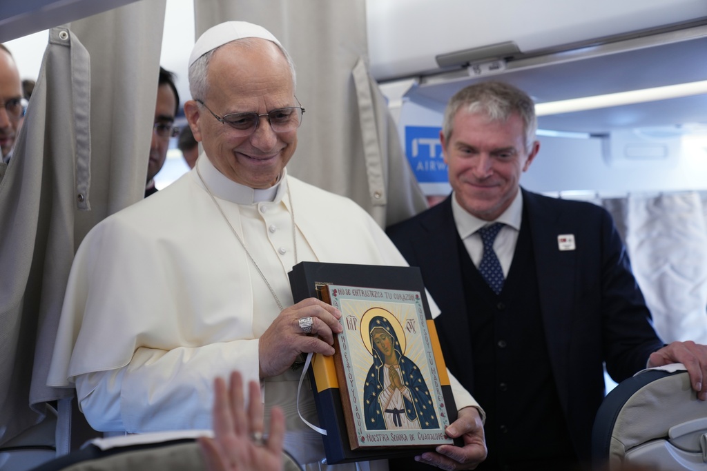 Pope Leo XIV greets reporters aboard a flight on his way to Ankara, Turkey, for a six-day trip to Turkey and Lebanon, Thursday, Nov. 27, 2025. (AP Photo/Domenico Stinellis, Pool)