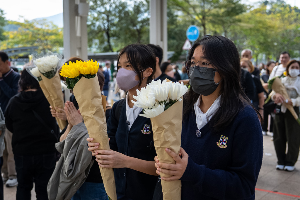 People offer flowers for the victims near the site of a deadly Wednesday fire at Wang Fuk Court, a residential estate in the Tai Po district of Hong Kong's New Territories on Monday, Dec. 1, 2025. (AP Photo/Chan Long Hei)