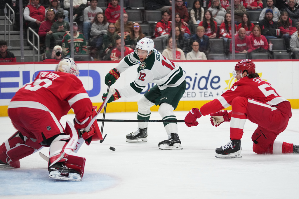 Detroit Red Wings defenseman Moritz Seider (53) defends Minnesota Wild left wing Matt Boldy (12) as he attempts to shoot on Detroit Red Wings goaltender Cam Talbot (39)in the first period of an NHL hockey game Sunday, April 5, 2026, in Detroit. (AP Photo/Paul Sancya)