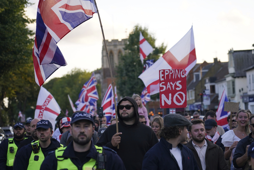 Police officers escort protesters near the Bell Hotel in Epping, London, Sunday, Aug. 31, 2025 after a temporary injunction that would have blocked asylum seekers from being housed at the hotel was overturned. (AP Photo/Alberto Pezzali)