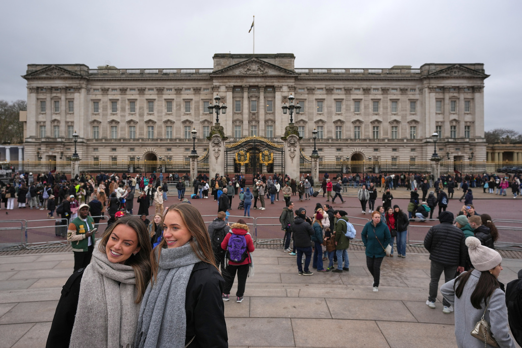 Visitors pose for pictures in front of Buckingham Palace in London, Thursday, Feb. 19, 2026 after Andrew Mountbatten-Windsor has been arrested by British police on suspicion of misconduct in public office. (AP Photo/Kin Cheung)