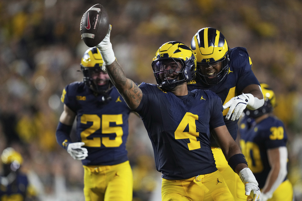 Michigan edge TJ Guy, center, celebrates with defensive lineman Damon Payne after intercepting the ball during the first half of an NCAA college football game against New Mexico, Saturday, Aug. 30, 2025, in Ann Arbor, Mich. (AP Photo/Ryan Sun)