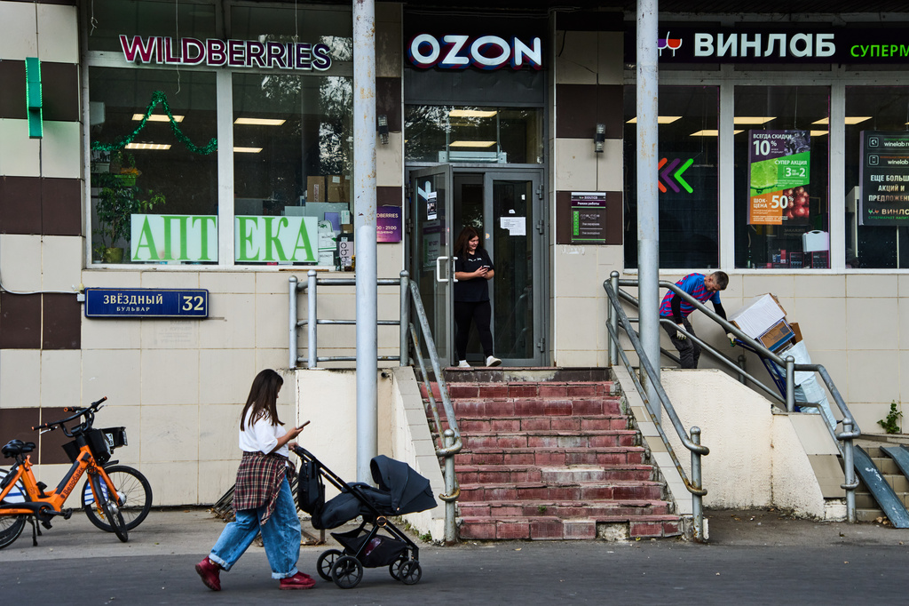 A woman pushes a baby stroller past a shopping area featuring an outlet of Russia's major online retailer Wildberries in Moscow on Wednesday, July 22, 2026. (AP Photo/Alexander Zemlianichenko)