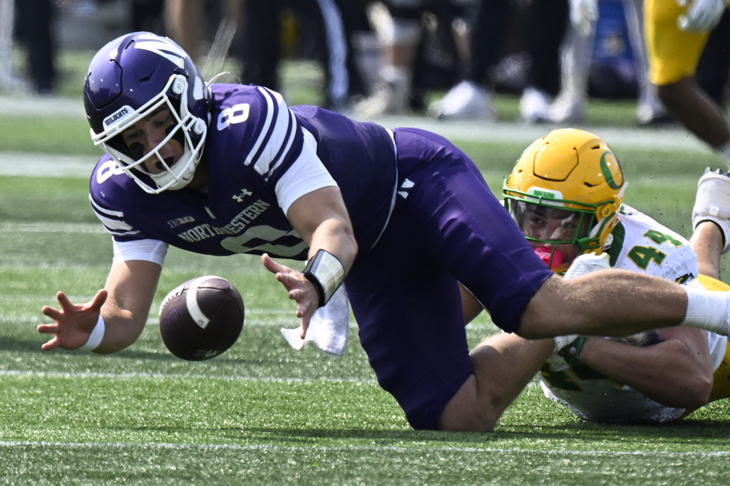 Northwestern quarterback Preston Stone (8) recovers a fumble while Oregon linebacker Teitum Tuioti (44) defends during the first half of an NCAA college football game on Saturday, Sept. 13, 2025 in Evanston, Ill. (AP Photo/Matt Marton)
