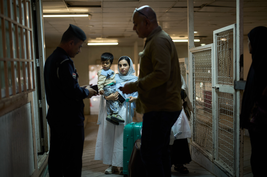 An Iraqi border police officer checks the passports of people arriving from Iran as they cross the Shalamcheh border crossing between Iran and Iraq, near Basra, Iraq, Sunday, March 29, 2026. (AP Photo/Leo Correa)