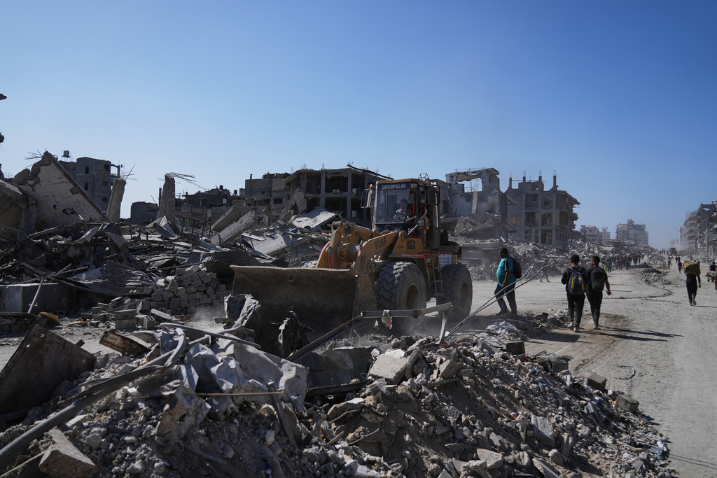 A Palestinian operates a mechanical shovel to clear debris from the heavily damaged Al-Jalaa Street in Gaza City, Saturday, Oct. 11, 2025, after Israel and Hamas agreed to a pause in their war and the release of the remaining hostages. (AP Photo/Abdel Kareem Hana)