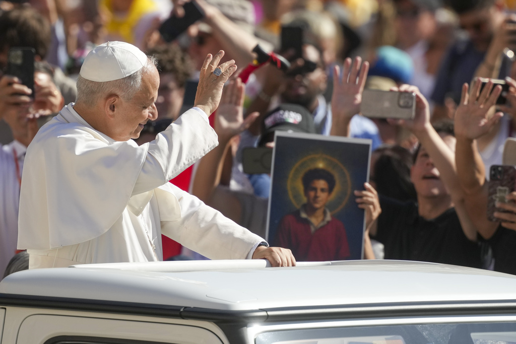 Pope Leo XIV waves to faithful holding a picture of Blessed Carlo Acutis, who will be canonized Sunday, as he arrives in St. Peter's Square at the Vatican for an open-air jubiliar audience Saturday, Sept. 6, 2025. (AP Photo/Andrew Medichini)