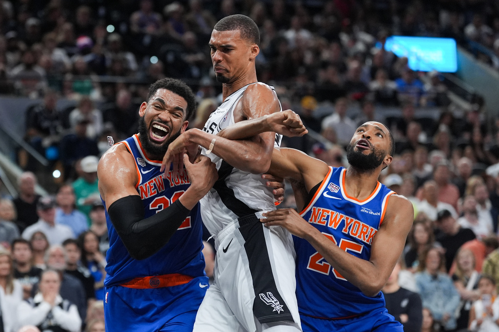 New York Knicks center Karl-Anthony Towns, left, and New York Knicks guard Mikal Bridges, right, pressure San Antonio Spurs forward Victor Wembanyama during the first half of Game 2 of the NBA Finals basketball series, Friday, June 5, 2026, in San Antonio. (AP Photo/Eric Gay)