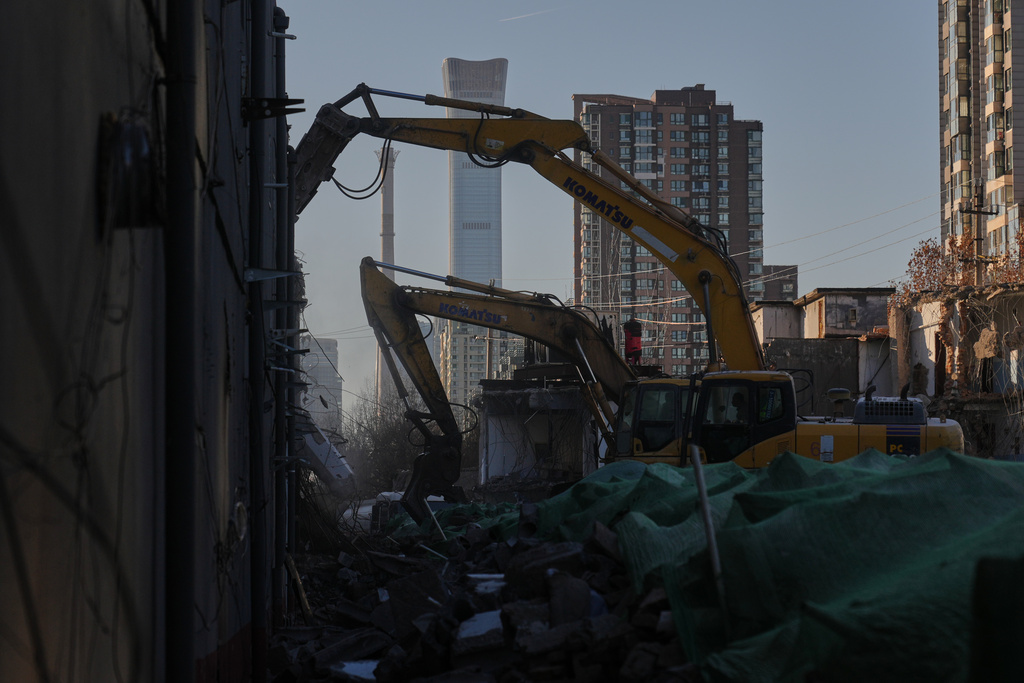 Workers using heavy machineries to demolish an old building near a residential area in Beijing, Tuesday, Dec. 23, 2025. (AP Photo/Andy Wong)