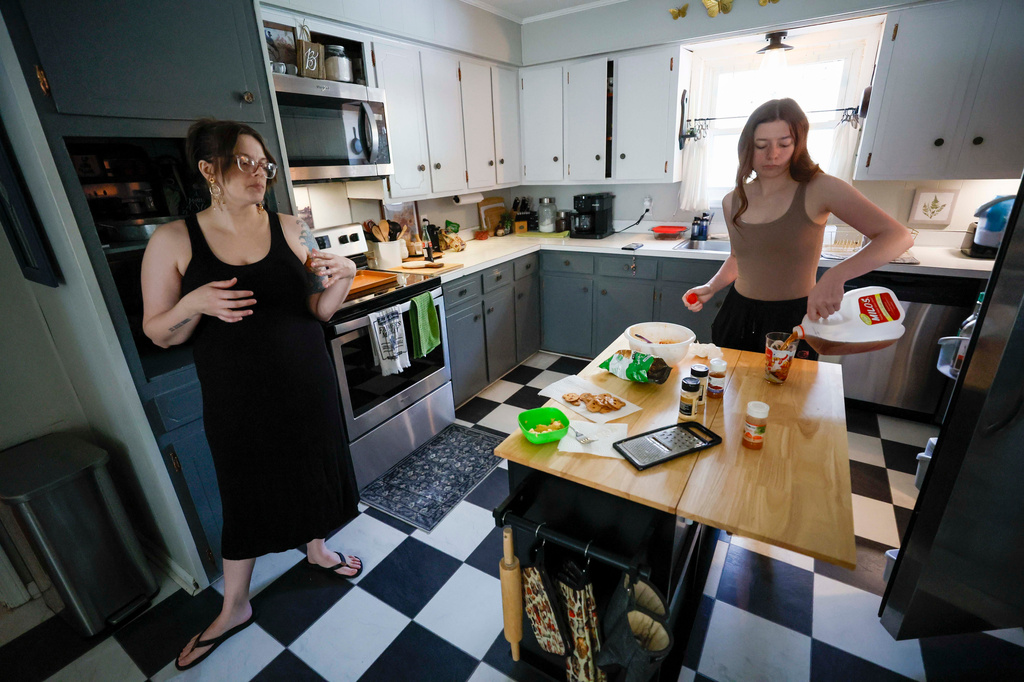 Emelia Pierce, 14, pours a glass of store-bought sweet tea while talking with her mother, Stormy Bost, in their kitchen in Calhoun, Ga., on March 29, 2026. (Miguel Martinez/Atlanta Journal-Constitution via AP)