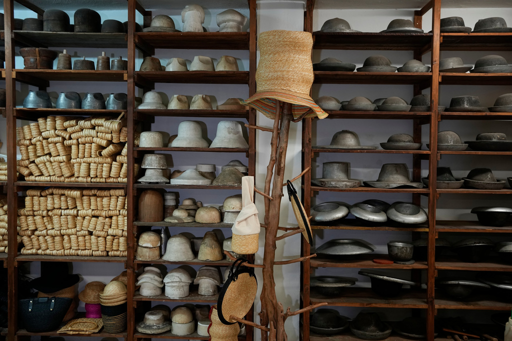 Hats are displayed alongside materials using in their production on hangers and shelves at a shop in Athens, Greece, Tuesday, Aug. 11, 2026. (AP Photo/Thanassis Stavrakis)
