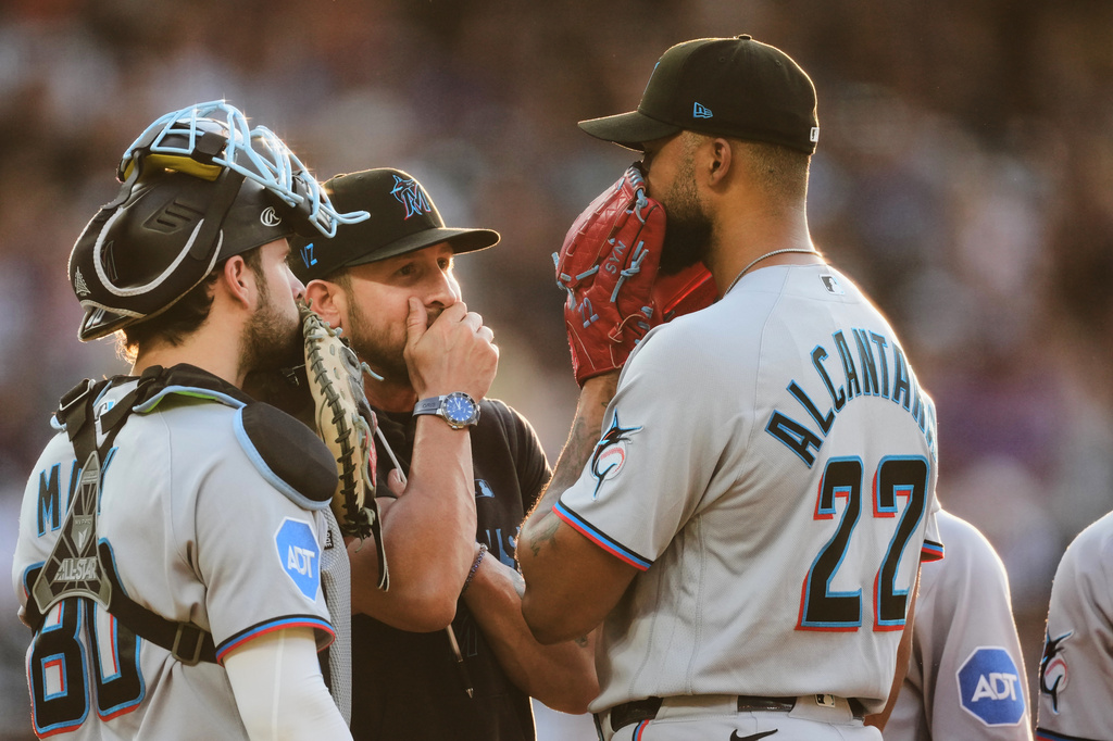 Miami Marlins pitching coach Daniel Moskos, second from left, confers with starting pitcher Sandy Alcantara (22) and catcher Joe Mack, left, in the third inning of a baseball game against the Colorado Rockies, Monday, June 29, 2026, in Denver. (AP Photo/David Zalubowski)