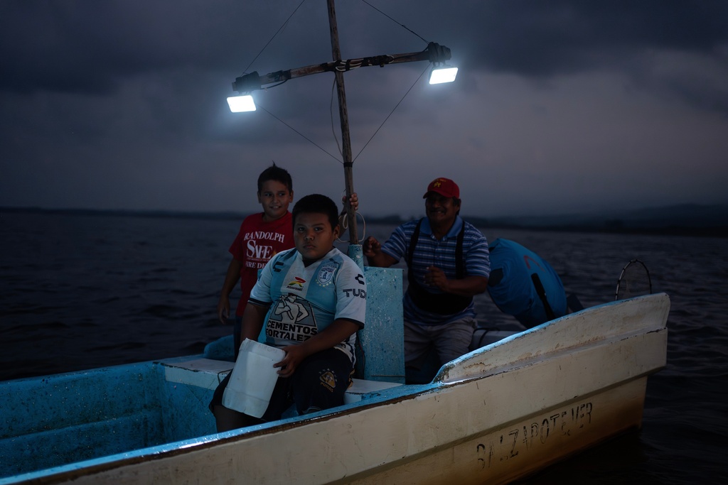 Fisherman Pancho Contreras sails at sea with young fishermen as night falls near Los Arrecifes, Mexico, Oct. 26, 2025. (AP Photo/Felix Marquez)
