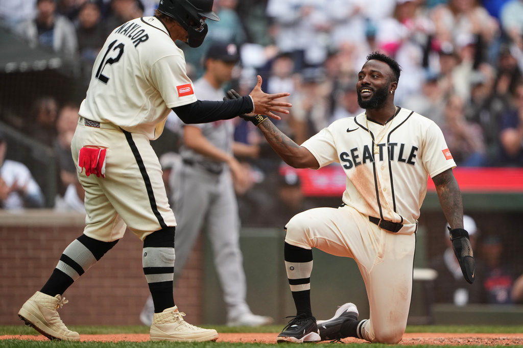 Seattle Mariners' Josh Naylor greets Randy Arozarena, right, after they scored on a two-run double from Luke Raley against the Houston Astros during the sixth inning of a baseball game, Sunday, April 12, 2026, in Seattle. (AP Photo/Lindsey Wasson)