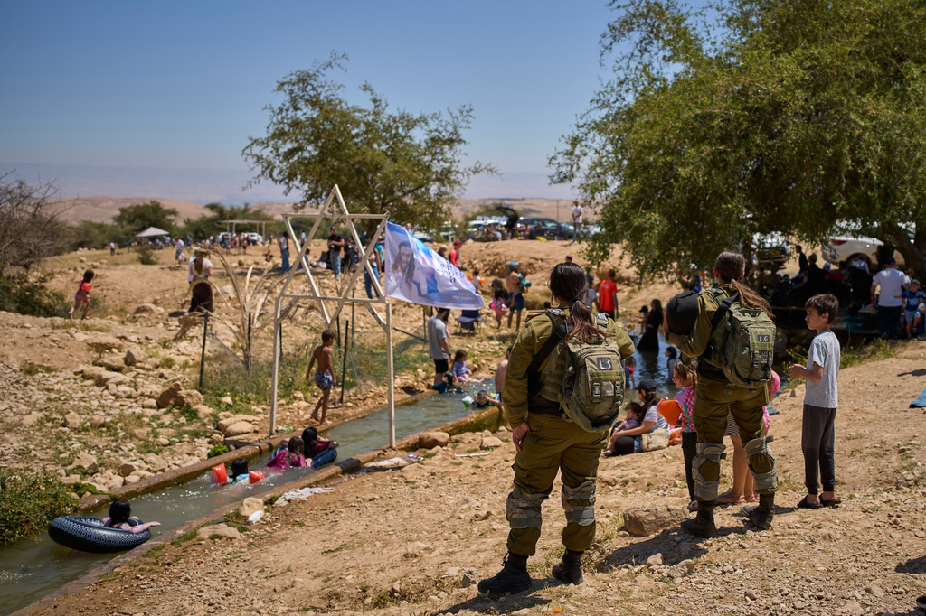 Israeli soldiers look on as Israeli settlers and others enjoy a day at a spring in the Jordan Valley during Israel's Independence Day, in Auja, in the occupied West Bank, Wednesday, April 22, 2026.(AP Photo/Ohad Zwigenberg)