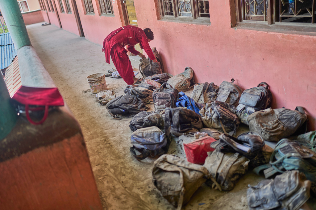 A mother searches for her child's bag from a pile extracted from the mud brought in by the recent flash floods, at the Shree Bagheswori Madhyamik School in Galchhi, Dhading district of Nepal Sunday, Aug. 30, 2026. (AP Photo/Niranjan Shrestha)