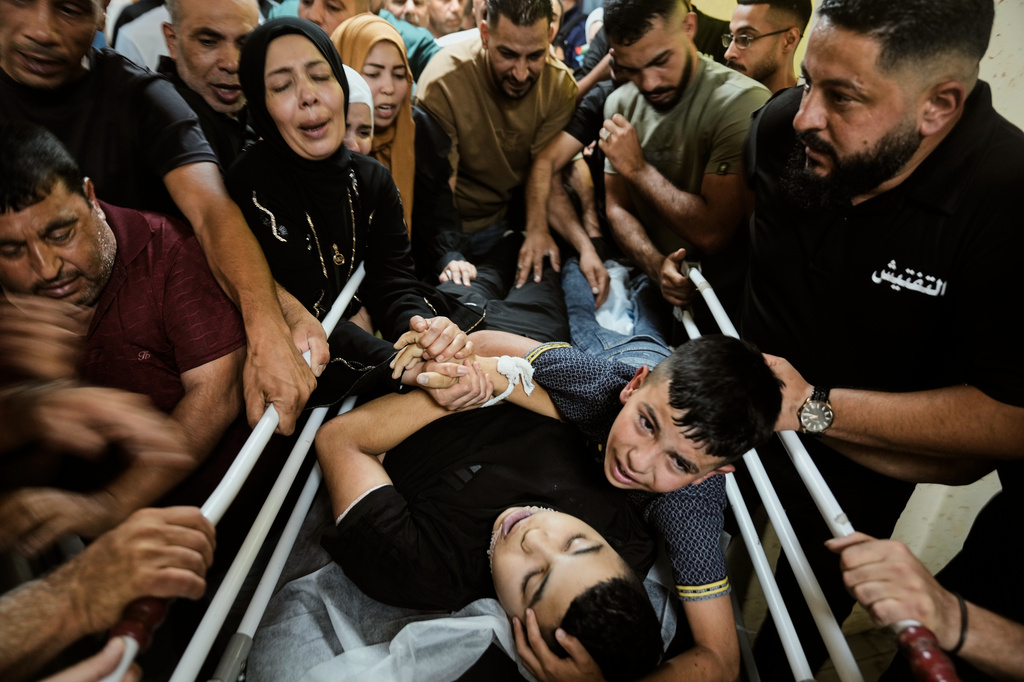 Mohammed Ajouri mourns over the body of his brother Islam Ajouri, 14, who, according to the Palestinian Ministry of Health, was killed by Israeli forces, as his body is brought to the hospital in the West Bank city of Nablus, Sunday, Aug. 23, 2026. (AP Photo/Majdi Mohammed)