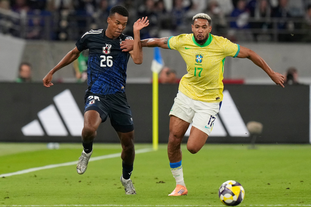 Japan's Henry Hiroki Mochizuki, left, against Brazil's Joelinton during the friendly soccer match between Japan and Brazil Tuesday, Oct. 14, 2025, in Tokyo. (AP Photo/Eugene Hoshiko)