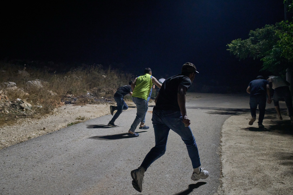 Palestinians run for cover after shots are fired during an Israeli settler attack on the West Bank village of Sinjil, Friday, July 17, 2026. (AP Photo/Leo Correa)