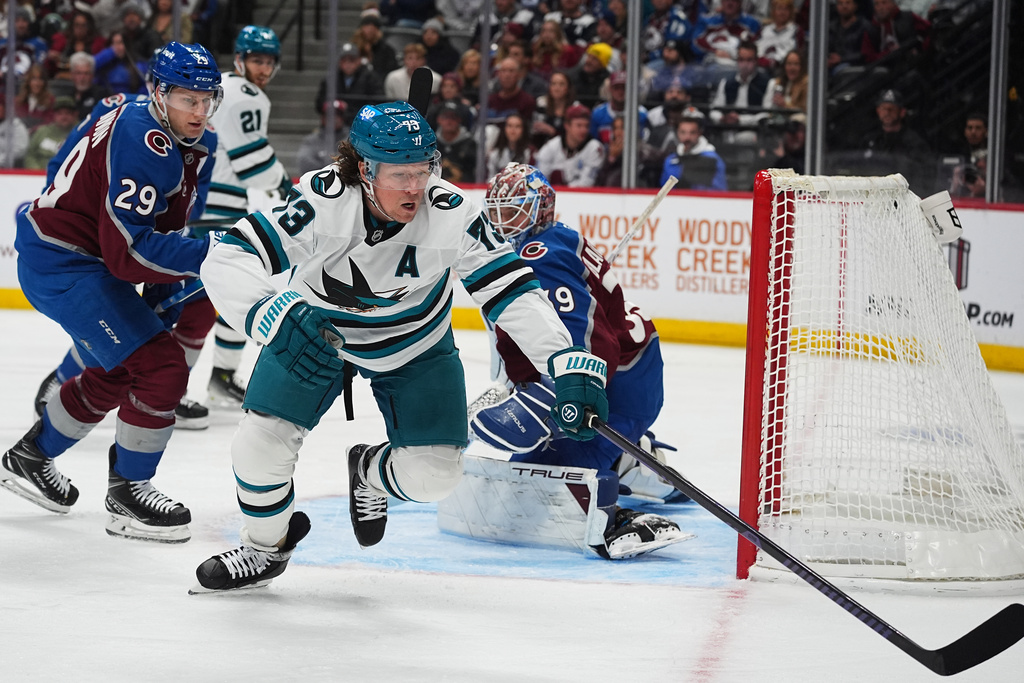 San Jose Sharks center Tyler Toffoli, front, pursues the puck as Colorado Avalanche center Nathan MacKinnon, back left, and goaltender Mackenzie Blackwood defend in the second period of an NHL hockey game, Wednesday, Nov. 26, 2025, in Denver. (AP Photo/David Zalubowski)