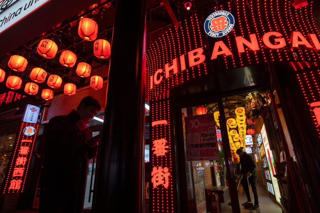 A man smokes outside a building known for its Japanese restaurants in Beijing, on Nov. 25, 2025. (AP Photo/Ng Han Guan)