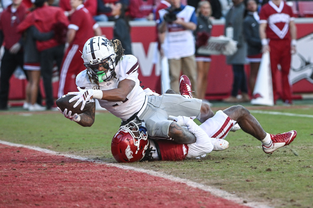 Mississippi State wide receiver Anthony Evans III (3) dives over Arkansas defensive back Jordan Young (4) to score a touchdown during the second half of an NCAA college football game Saturday, Nov. 1, 2025, in Fayetteville, Ark. (AP Photo/Michael Woods)