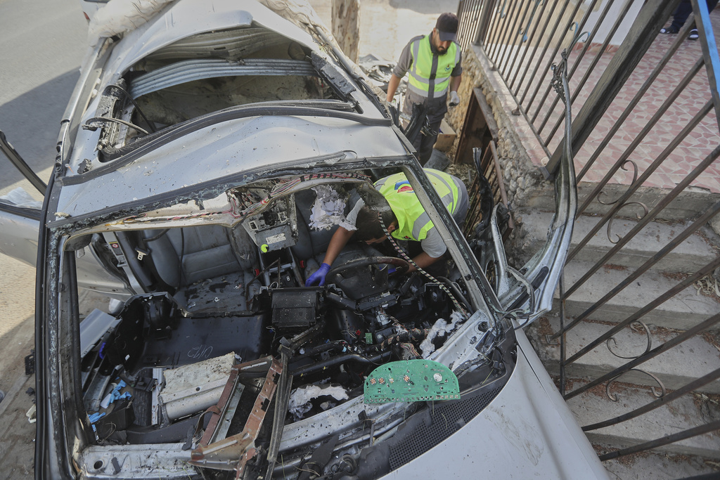 Civil defense workers inspect a damaged car hit Sunday in an Israeli drone strike that killed four members of the same family, in Bint Jbeil town, southern Lebanon, Monday, Sept. 22, 2025. (AP Photo/Mohammed Zaatari)