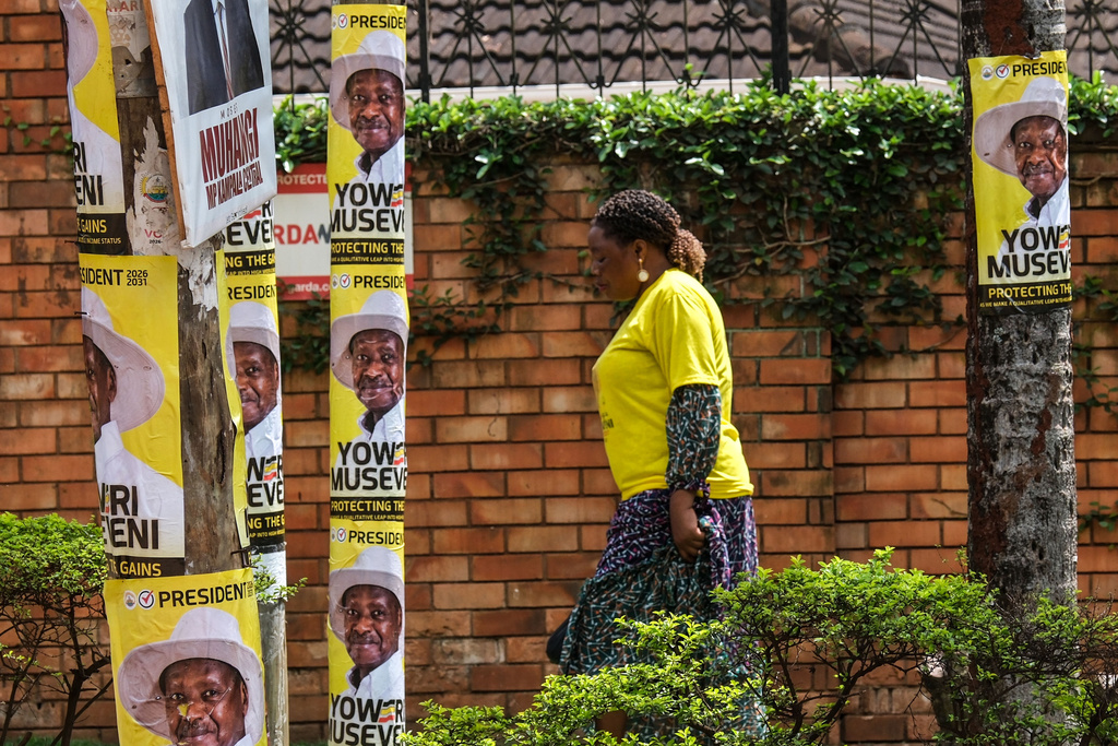 A supporter passes utility poles plastered with posters of Uganda's President and National Resistance Movement (NRM) presidential candidate Yoweri Museveni during a campaign rally in Kampala, Uganda, Tuesday, Jan. 13, 2026. (AP Photo/Samson Otieno)