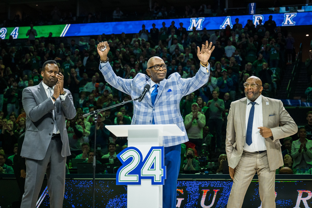 Former Dallas Mavericks player Mark Aguirre, center, reacts during his jersey retirement presentation at halftime during an NBA basketball game between the Mavericks and the Charlotte Hornets, Thursday, Jan. 29, 2026, in Dallas. (AP Photo/Jessica Tobias)