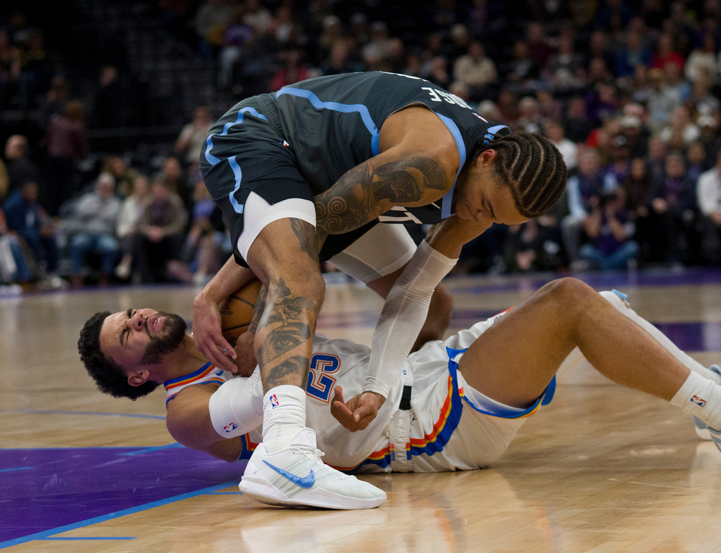Utah Jazz guard Keyonte George, top, and Oklahoma City Thunder guard Ajay Mitchell (25) fight for the ball during the first half of an NBA basketball game Sunday, Dec. 7, 2025, in Salt Lake City. (AP Photo/Bethany Baker)