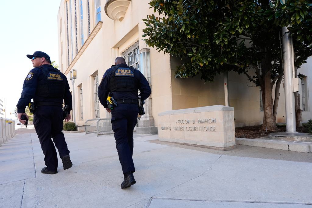 Officers with the Department of Homeland Security walk on the sidewalk outside the Eldon B. Mahon U.S. Courthouse during a trial for nine people connected to a 2025 shooting outside an ICE detention facility, in Fort Worth, Texas, Thursday, March 12, 2026. (AP Photo/Tony Gutierrez)