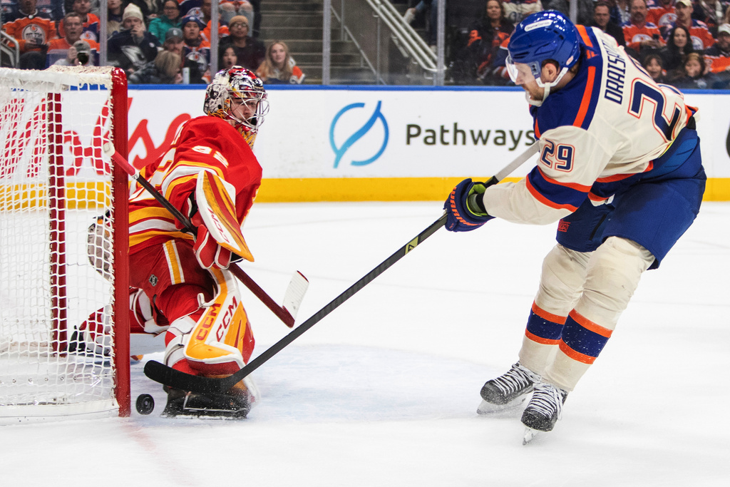 Calgary Flames goalie Dustin Wolf (32) stops a shot by Edmonton Oilers' Leon Draisaitl (29) during second period NHL action in Edmonton, Alberta, Tuesday, Dec. 23, 2025. (Amber Bracken/The Canadian Press via AP)