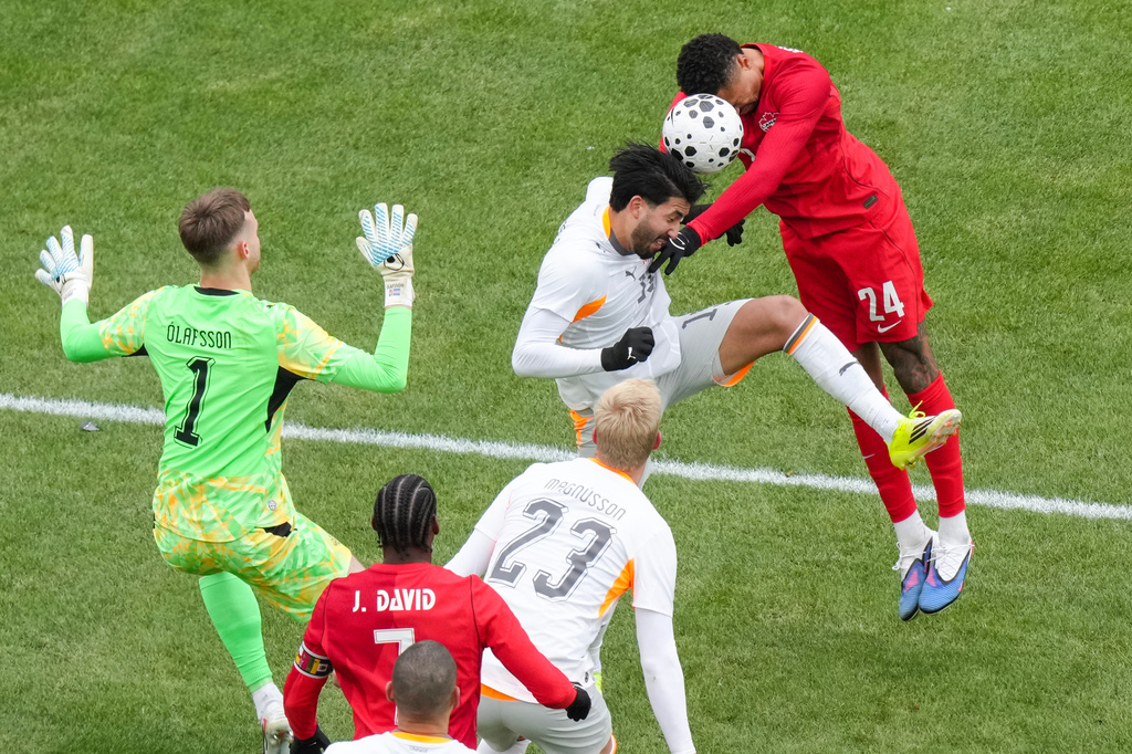 Canada's Daniel Jebbison (24) tries to send a header towards the Iceland goal as he is challenged by Iceland's Mikael Egill Ellertsson during the second half of an international friendly soccer match in Toronto, Saturday March 28, 2026. (Chris Young/The Canadian Press via AP)