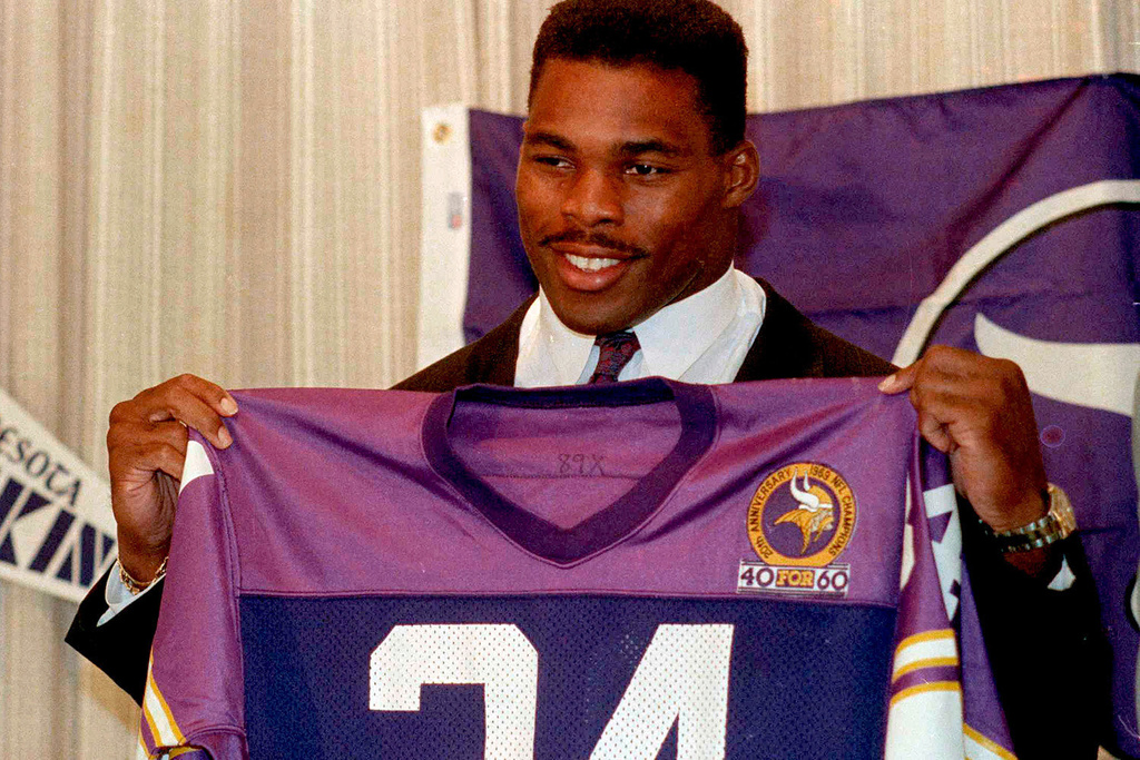 FILE - Former Dallas Cowboys running back Herschel Walker holds up jersey as he is introduced during an NFL football news conference to announce the trade of five players and seven draft choices by the Minnesota Vikings for the leading NFC rusher, Oct. 13, 1989, in Bloomington, Minn. (AP Photo/Jim Mone, File)