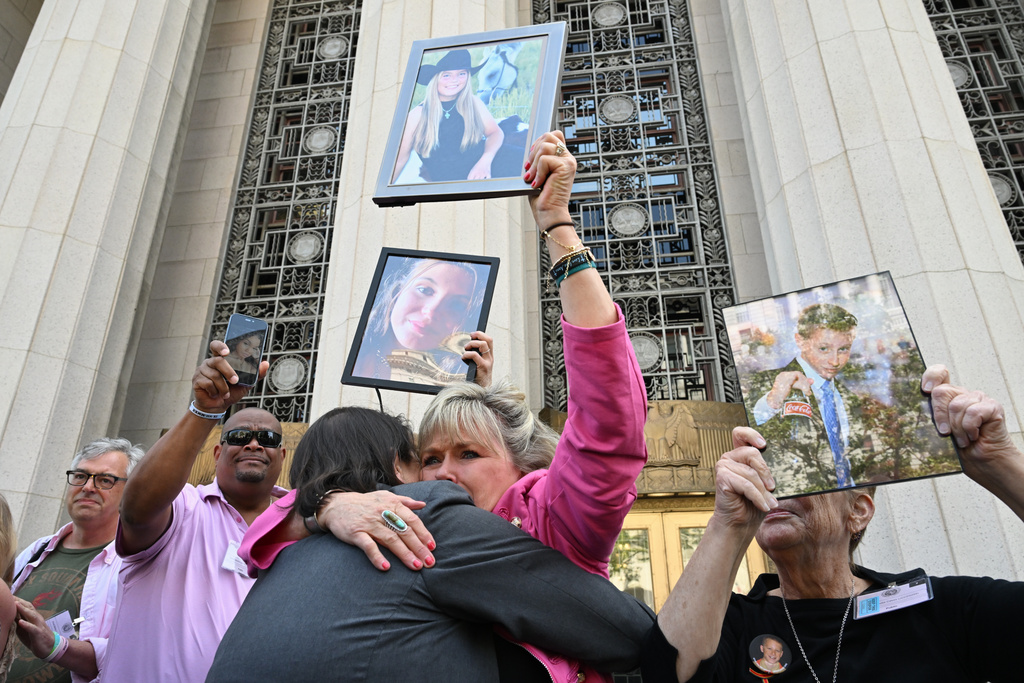 Lori Schott, center, is embraced as she holds up a photo of her daughter Annalee Schott, after the verdict in a landmark trial over whether social media platforms deliberately addict and harm children at Los Angeles Superior Court, Wednesday, March 25, 2026, in Los Angeles. (AP Photo/William Liang)