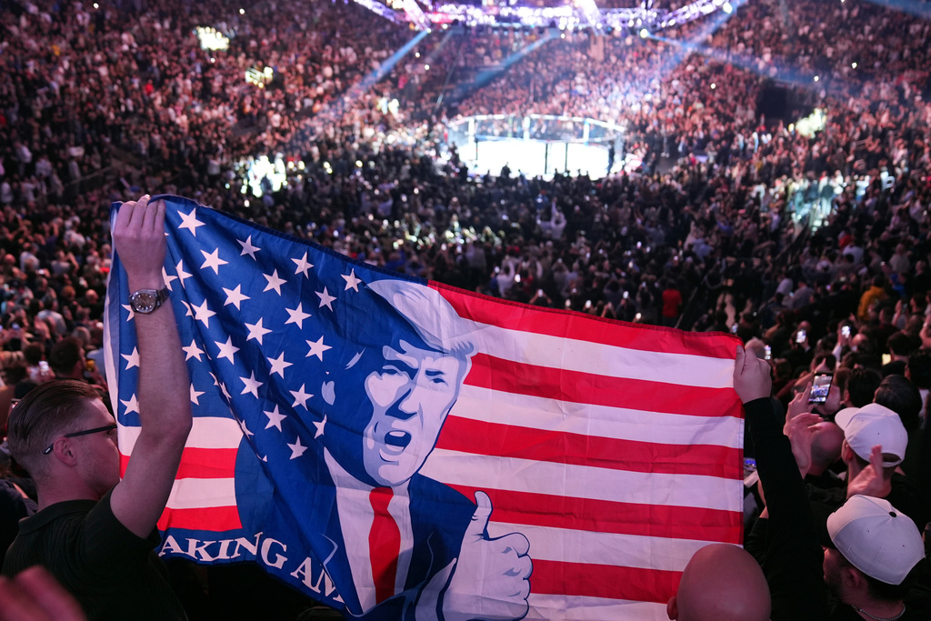 FILE - People hold a flag as President-elect Donald Trump arrives at UFC 309 at Madison Square Garden, Nov. 16, 2024, in New York. (AP Photo/Evan Vucci, File)