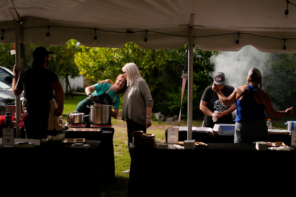 Mary Berry, executive director of the Berry Center, right, greets Randi Densford, left, with a kiss on the head, as she cooks during the Beef Bash 2025 tasting event at the Berry Center, Saturday, Oct. 11, 2025, in New Castle, Ky. (AP Photo/Carolyn Kaster)