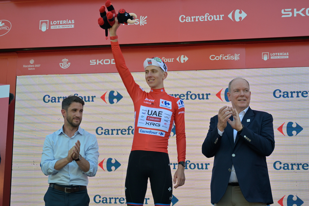 Slovenia's Tadej Pogacar, wearing the overall leader's red jersey celebrates on the podium after the second stage of the La Vuelta cycling race, with start in Monaco and finish in Manosque, France, Sunday, Aug. 23, 2026. (AP Photo/Philippe Magoni)