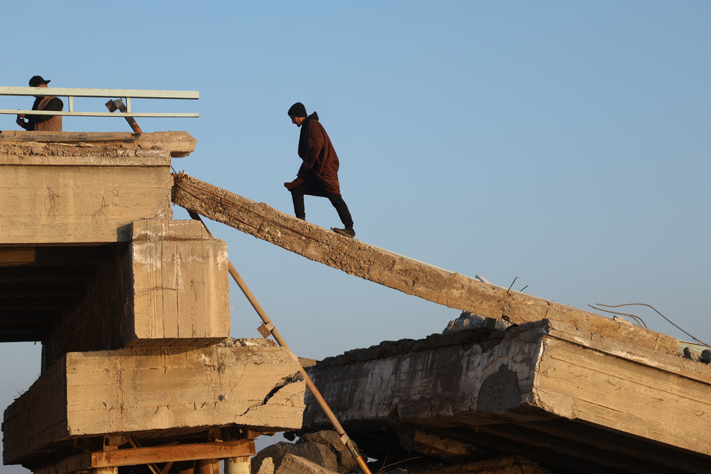 People cross a damaged bridge over the Euphrates River in Raqqa, Syria, Sunday, Jan. 25, 2026. (AP Photo/Ghaith Alsayed)