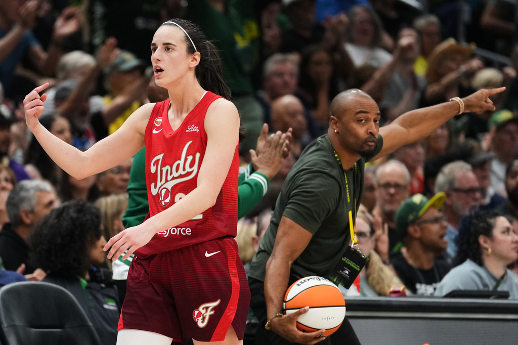 Indiana Fever guard Caitlin Clark points for possession as former Seattle Seahawks wide receiver Doug Baldwin, right, picks up the ball and calls for Seattle Storm possession during the first half of a WNBA basketball game, Tuesday, July 28, 2026, in Seattle. (AP Photo/Lindsey Wasson)