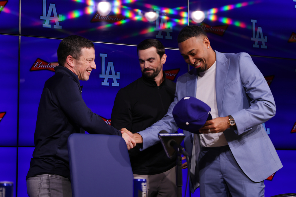 Edwin Díaz, right, shakes hands with President of Baseball Operations Andrew Friedman, left, while standing next to General Manager Brandon Gomes during his introduction as a new member of the Los Angeles Dodgers baseball team Friday, Dec. 12, 2025, in Los Angeles. (AP Photo/Ethan Swope)