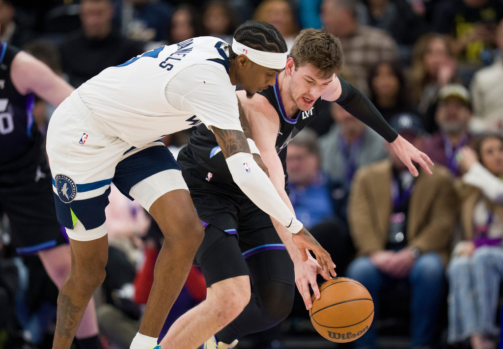 Minnesota Timberwolves forward Jaden McDaniels, left, and Utah Jazz center Kyle Filipowski, behind, fight for the ball during the first half of an NBA basketball game Tuesday, Jan. 20, 2026, in Salt Lake City. (AP Photo/Bethany Baker)