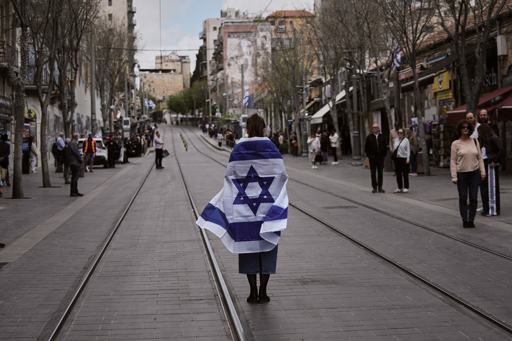 People stand still to observe two minutes of silence as air raid sirens sound, marking Israel's annual Memorial Day for the soldiers who died in the nation's conflicts and victims of nationalistic attacks, in Jerusalem, Tuesday, April 21, 2026. (AP Photo/Mahmoud illean)