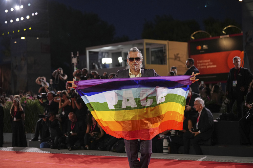 Piero Pelu holds a flag that reads 'Peace' on the red carpet for the film 'Father Mother Sister Brother' during the 82nd edition of the Venice Film Festival in Venice, Italy, on Sunday, Aug. 31, 2025. (Photo by Alessandra Tarantino/Invision/AP)