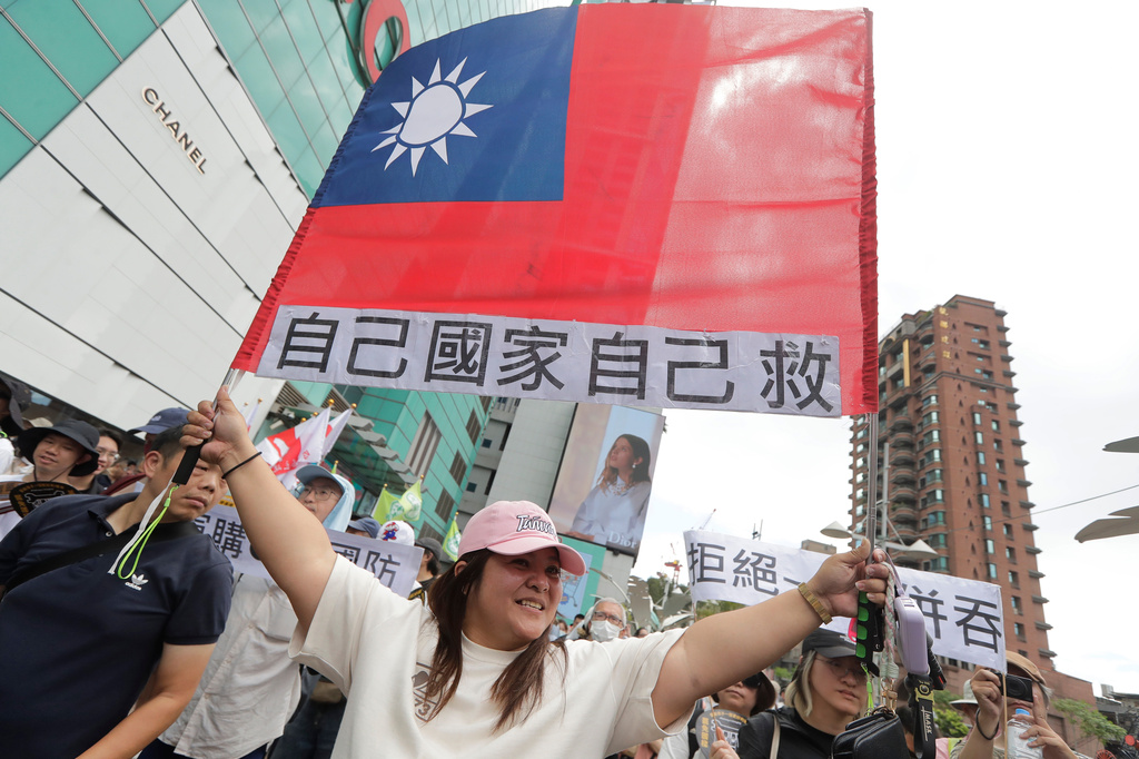 A woman holds up Taiwan's flag with a slogan reading, "Save our own country!" in Taipei, Taiwan, Saturday, May 23, 2026. (AP Photo/Chiang Ying-ying)