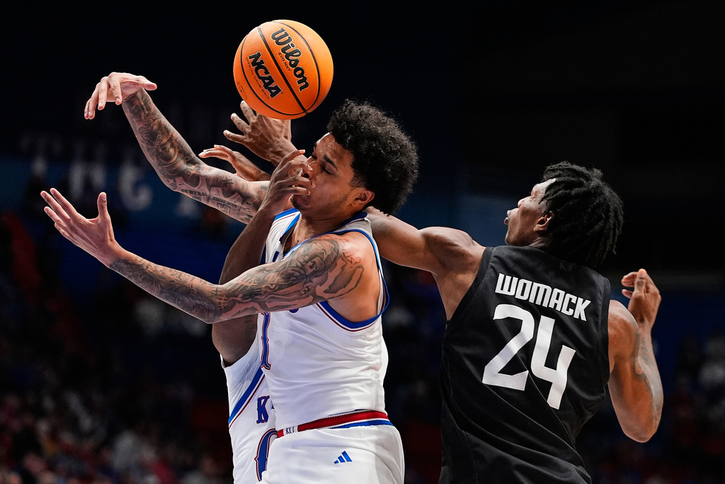 Kansas guard Jayden Dawson, left, and Towson guard Jaquan Womack (24) battle for the ball during the second half of an NCAA college basketball game Tuesday, Dec. 16, 2025, in Lawrence, Kan. (AP Photo/Charlie Riedel)